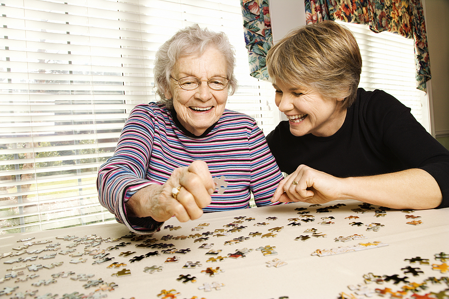 Elderly parent and daughter work on jigsaw puzzle